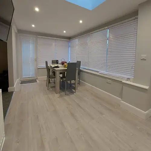 A room with a table, chairs, and a flat screen tv.