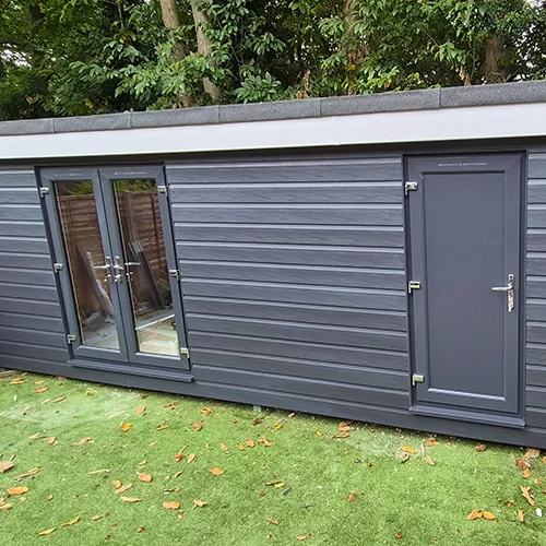 A large gray shed sitting on top of a lush green field.